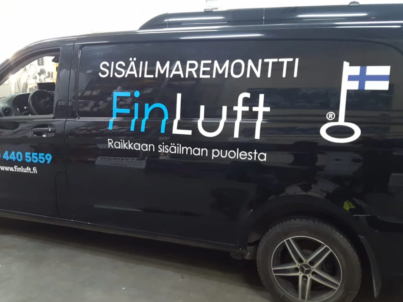 FinLuftin mustan pakettiauton sinivalkoinen mainosteippaus