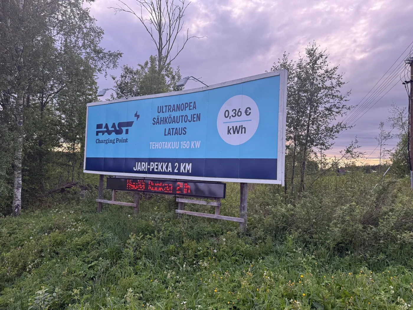 Faast Charging Pointin suuri tienvarsimainos suomalaisessa metsämaisemassa